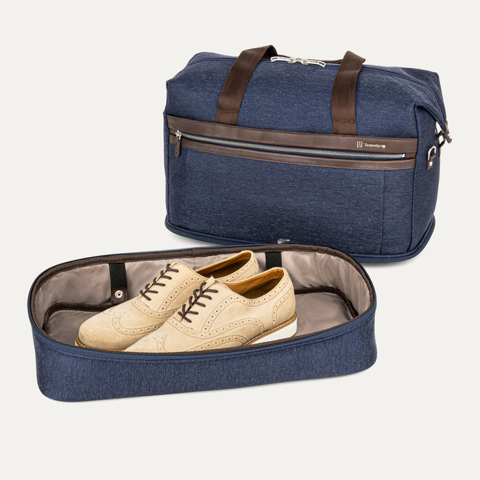a view of the true navy travelpro platinum elite drop-bottom weekender bag with the bottom section completely removed, showing a pair of tan shoes inside the detached compartment and the main bag sitting behind it.
