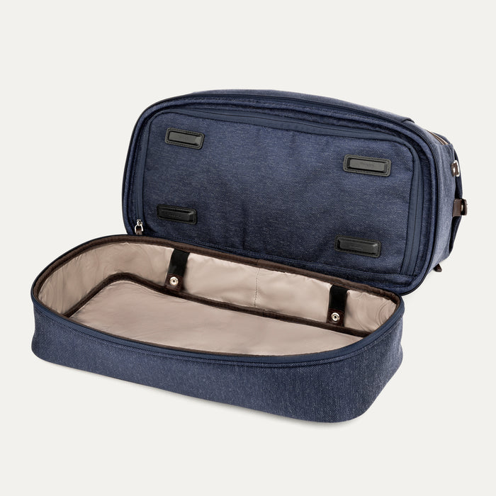 interior view of the open drop-bottom compartment on the true navy travelpro platinum elite weekender bag, showing the spacious empty section with a light tan lining and internal snap-button straps.