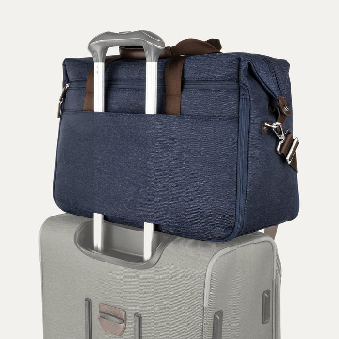 Rear view of the Travelpro Platinum Elite Soft Duffel in True Navy, showing back sleeve secured over telescoping suitcase handle, brown leather trim, and silver hardware against a white background.