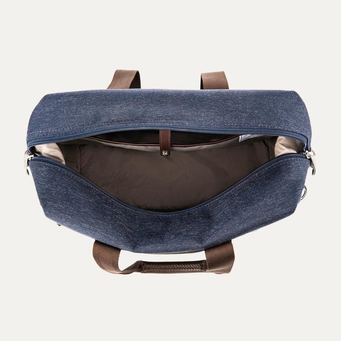 Top view of the Travelpro Platinum Elite Soft Duffel in True Navy, showing open main compartment with tan interior lining, brown leather handles, and silver zipper hardware against a white background.