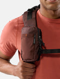 Person wearing a garnet crossbody bag on a plain background