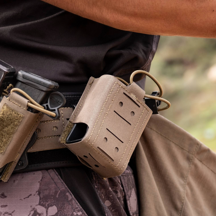 Close-up of Kore Essentials tactical mag pouches attached to a person's pants with a blurred natural background
