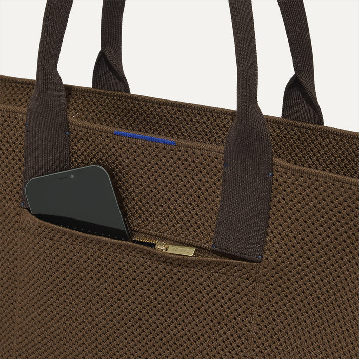 A closeup of The Classic Tote in Cinnamon Open Knit, focusing on the exterior zip pocket.