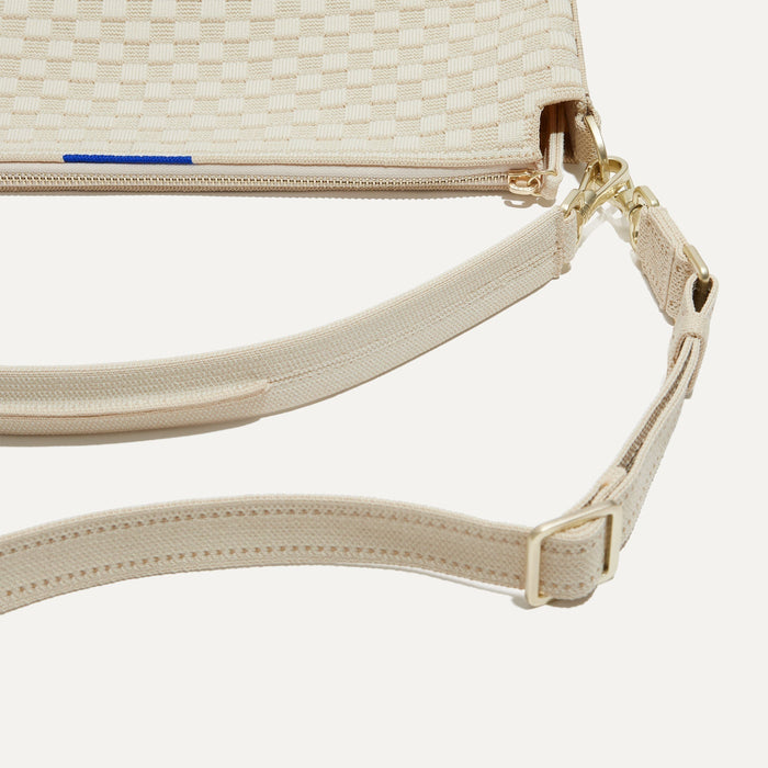 A closeup of The Daily Crossbody Bag in White Sand, showing the smooth zipper closure and soft, flexible handle.