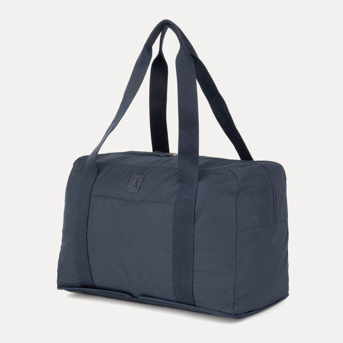 Angled view of the Travelpro Essentials SparePack Foldable Duffel 2.0 in Navy, showcasing the bag's sleek profile, spacious main compartment, and durable carry handles.