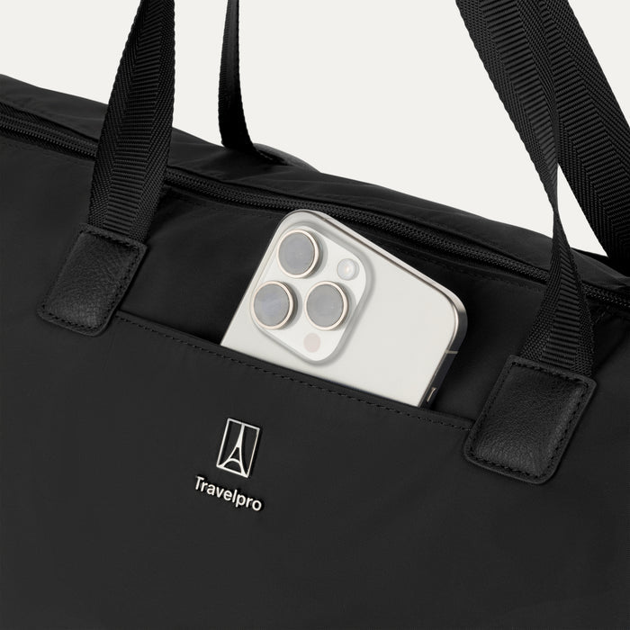 Close-up detail view of the Travelpro Essentials SparePack Foldable Tote 2.0 in Black, highlighting the QuickSlip front pocket with a smartphone tucked inside for convenient, quick access to essentials.