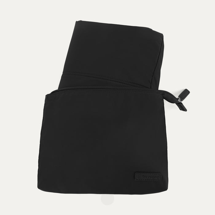Close-up view of the Travelpro Essentials SparePack Foldable Tote 2.0 in Black, showing the bag fully packed and zipped into its compact, flat storage pouch, highlighting the embossed Travelpro branding on the front.