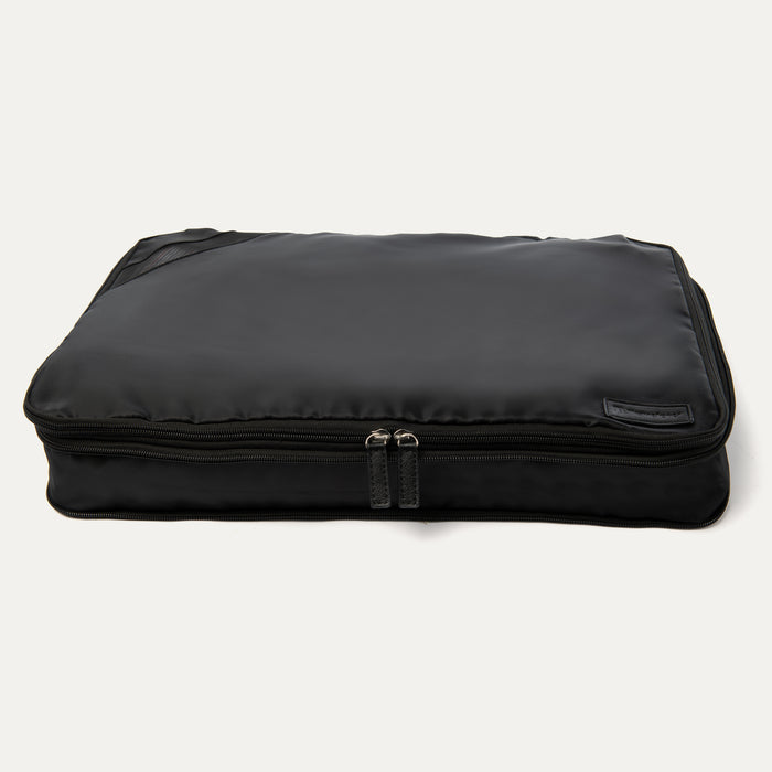 A black Travelpro Essentials XL expandable/compressible packing cube with a zipper.