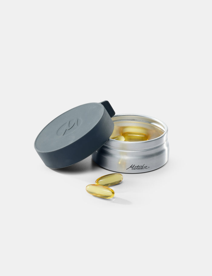 Open container of supplements with pills on a white background