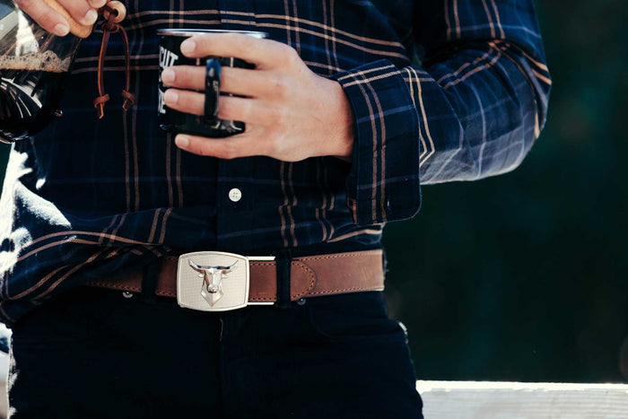 Man Wearing a navy flannel and a Brown Kore Essentials Buffalo Leather Gun Belt with a Bull Buckle
