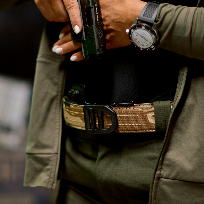 Closeup shot of a woman wearing a Kore Essentials 1.5" desert tiger stripe camo nylon edc gun belt with an X5 buckle.