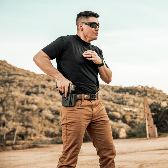 A man in tactical wears a Kore Essentials multicam regular tactical nylon gun belt gear, while drawing his firearm at a shooting range.
