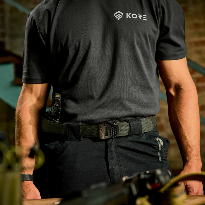 Person wearing a black KORE shirt with a ranger green Kore Essenitals gun belt